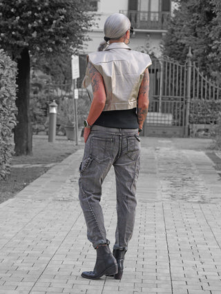 Person von hinten mit silbernem Haar trägt die OFF#DLY Weste Mariella black, eine kurze, glänzende Weste über schwarzem Top, kombiniert mit grauen Cargo-Hosen und schwarzen Stiefeletten.