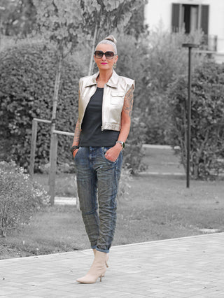 Person trägt OFF#DLY Denim Nika dark blue mit lockerem Schnitt und umgeschlagenem Saum, kombiniert mit metallic-silberner Weste, passenden Boots und sichtbaren Tattoos, stilvoll im lässigen Outdoor-Look.