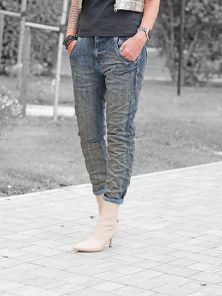 OFF#DLY Denim Nika dark blue Jeans, lässig geschnitten, umgeschlagene Bündchen, getragen mit beigen Stiefeletten. Ideal für einen modernen, entspannten Look. Sichtbar sind auch ein Armband und eine Smartwatch.