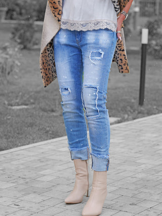 Person trägt OFF#DLY Denim Lara lightblue, eine hellblaue, distressed Skinny Jeans mit umgeschlagenen Bündchen, kombiniert mit spitzen, beigefarbenen Stiefeletten. Leopard-Muster Mantel und Spitzenbluse sichtbar.