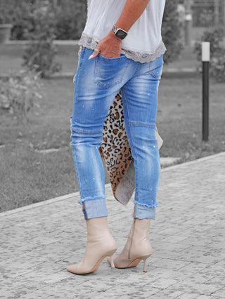OFF#DLY Denim Lara lightblue: Leicht zerstörte, hellblaue Skinny-Jeans mit umgeschlagenem Saum und Farbspritzern, kombiniert mit spitz zulaufenden Stiefeletten und einem leopardengemusterten Accessoire im Hintergrund.