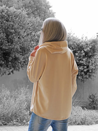 Person von hinten in einem OFF#DLY Hoody Alva beige, Kapuze haltend, im Regen. Beiger Hoodie mit goldschimmerndem Animal-Print, lässig-modern, perfekt für urbanen Stil.