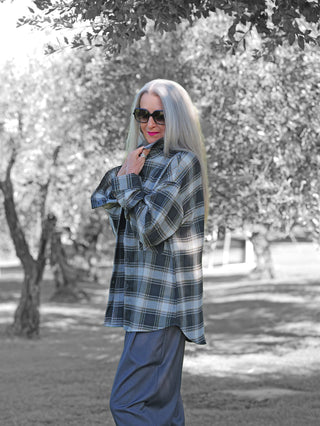 Die OFF#DLY Checker Bluse Amelia black/grey wird von einer Person im Freien getragen, mit hochgehaltener Kragen und entspanntem Schnitt, kombiniert mit einer lässigen, modernen Ausstrahlung.
