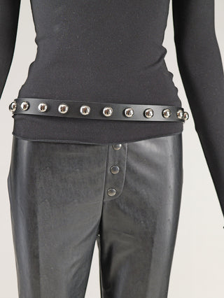 Der OFF#DLY Gürtel Leder silver Ball black wird um eine schwarze Hose getragen, mit glänzenden silbernen Halbkugel-Nieten auf einem schmalen, schwarzen Ledergürtel als auffälliges Detail.