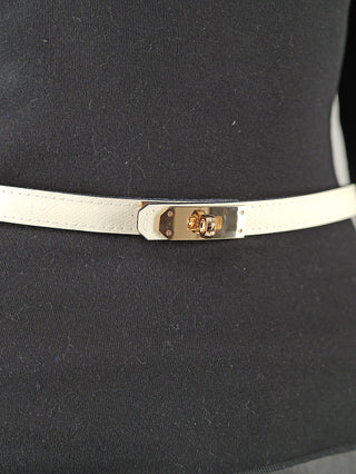 Nahaufnahme des OFF#DLY Gürtel Leder beige mit goldfarbener Drehverschluss-Schließe, auf schwarzem Stoff. Der Gürtel aus 100% Leder ist 2 cm breit und bis Größe 42 verstellbar.