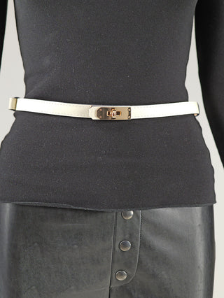 Nahaufnahme des OFF#DLY Gürtel Leder beige an einer Taille, schmaler Gürtel aus echtem Leder mit goldfarbener Schließe, getragen über einem schwarzen Oberteil und einem schwarzen Lederrock.