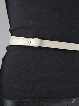 Nahaufnahme des OFF#DLY Gürtel Leder beige, der um eine schwarze Kleidung getragen wird. Zu sehen ist ein schmaler, cremefarbener Gürtel mit goldfarbenem Nieten-Detail, ohne sichtbare Schließe.