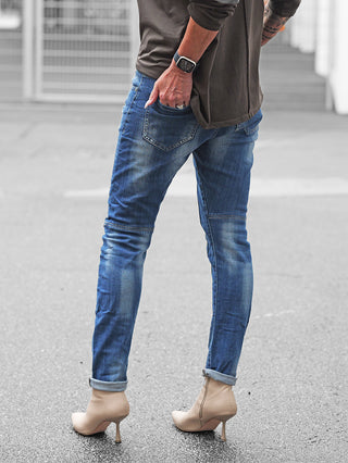 OFF#DLY Denim Bergamo midblue: Schmal geschnittene, figurbetonte Jeans mit leichten Used-Effekten, getragen mit beige Stiefeletten und einer Smartwatch, ideal für stilvolle, moderne Alltagslooks.