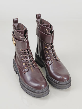OFF#DLY Boot BB/L brown: Frauen-Stiefeletten im Combat-Stil aus glänzendem Leder, vorn geschnürt, mit goldenen Ösen, dekorativer Schnalle am Knöchel und schwarzen, klobigen Sohlen.