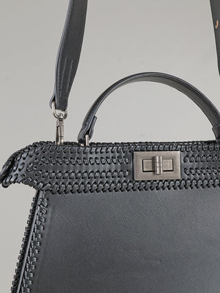Nahaufnahme der OFF#DLY Bag black: Schwarze Ledertasche mit Peitschennähten, kleinem Henkel, Schulterriemen und rechteckigem Drehverschluss in Gunmetall. Glatte Lederpaneele ergänzen das Design. Größe: 33 x 25 x 8 cm.