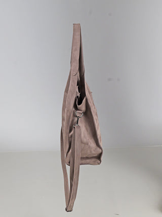 OFF#DLY Shoulder Bag taupe in Velour-Optik, zeigt eine weiche, leicht schlaffe Form mit einem langen, an einem Metallring befestigten Trageriemen, präsentiert aus seitlicher Ansicht.