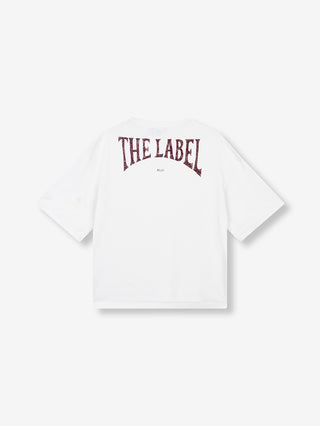 ALIX Back Logo Tee soft white zeigt ein schlichtes weißes T-Shirt mit kurzen Ärmeln. Auf der Rückseite prangt in distressed, bordeaux-roter Schrift „THE LABEL“ und darunter „ALIX“.