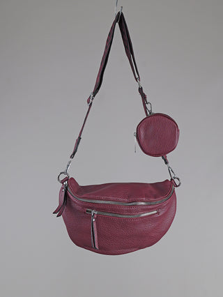 OFF#DLY Crossbody Bag bordeaux in burgunderrotem, genarbtem Kunstleder, mit Metallreißverschlüssen und verstellbarem Riemen. Inklusive passender, runder Münztasche am Riemen. Maße: 30x17 cm, Münztasche: 10 cm.