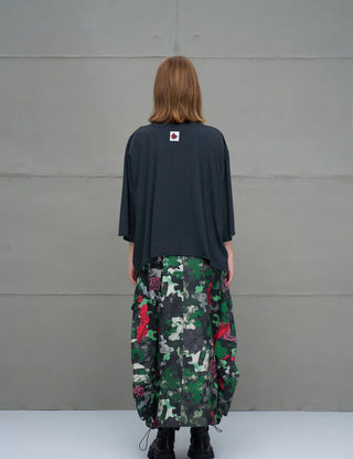 Person von hinten in einem #VDR Tee 18007 black, einem oversized, dunklen T-Shirt mit dreiviertellangen Ärmeln, vor einer grauen Wand. Das Shirt zeigt einen subtilen Ton-in-Ton Frontprint.