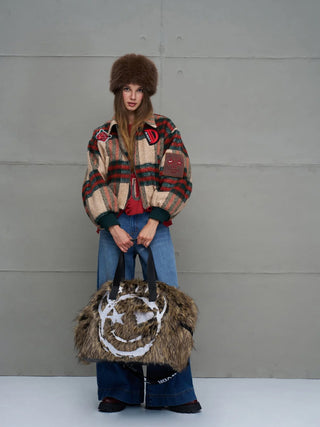 Junge Frau mit #VDR Rambo2 Bag aus Kunstfell, großem weißem Smiley-Motiv, schwarzem Webgriff, ideal für urbanen Look, vielseitig tragbar. Kombiniert mit modischer Winterkleidung, Retro-Casual-Stil.