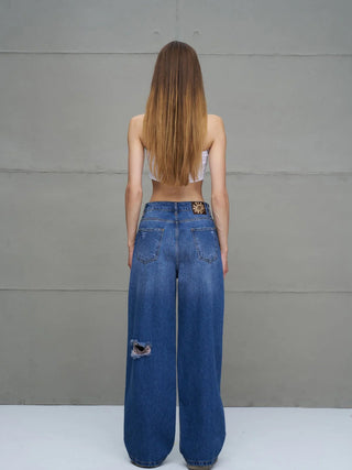 Person trägt #VDR Destroy Denim 18132 midblue mit hohem Bund und weitem Bein. Sichtbare Distressed-Stelle am linken Bein und Leder-Patch auf der Rückseite. Perfekter urbaner Look.