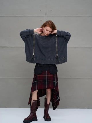 Das Modell trägt den #VDR Sweater 18005 anthrazit, ein oversized Sweatshirt mit seitlichen Zippern, kombiniert mit einem roten Tartanrock und burgunderfarbenen Stiefeln für einen dezenten Streetwear-Look.