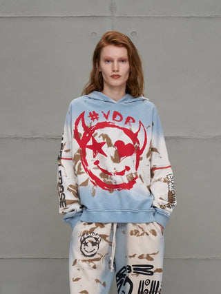 #VDR Sweatshirt 18000 blue/beige: Lässiger Hoodie mit rotem Smiley-Frontprint und braunen Splatter-Akzenten, kombiniert mit passenden Sweatpants, ideal für urbanen Streetstyle.