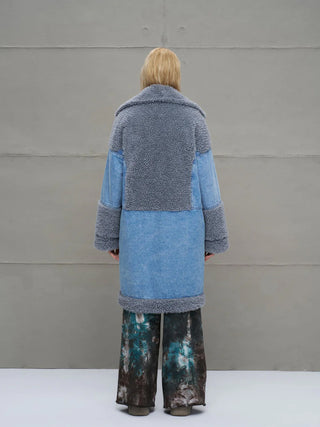 Rückansicht einer Person im #VDR Mantel 18077 blue, einem oversized Denim-Coat mit kuscheligem Faux-Fur-Kragen, breitem Revers und Bindegürtel, ideal für urbanen, luxuriösen Look.