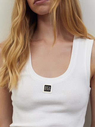 Nahaufnahme des BSB Top 210020 white: Weißes, geripptes Tanktop mit schwarzem ES3-Logo-Patch, ärmellosem Schnitt und rundem Halsausschnitt. Gezeigt wird ein Teil des Oberkörpers mit blonden Haaren.