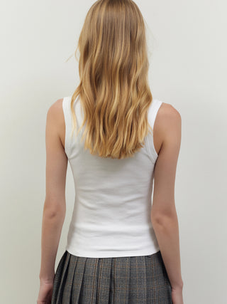 Person von hinten vor heller Wand, trägt BSB Top 210020 white, ein figurbetontes, weißes, ärmelloses Rippstrukturtop mit rundem Halsausschnitt. Kombiniert mit grauem, kariertem Faltenrock.