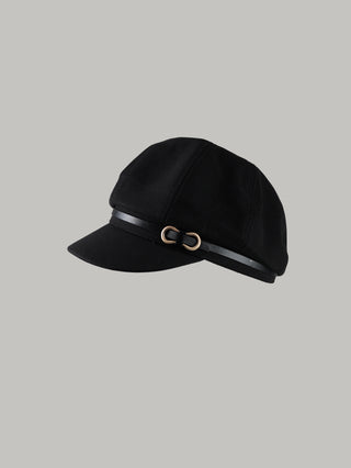 OFF#DLY Capello black: Schwarze Newsboy-Mütze mit weichem, gepaneltem Kopfteil, kurzem festen Schirm und schmalem Kunstlederband mit goldfarbener Schnalle, flach auf grauem Hintergrund liegend.