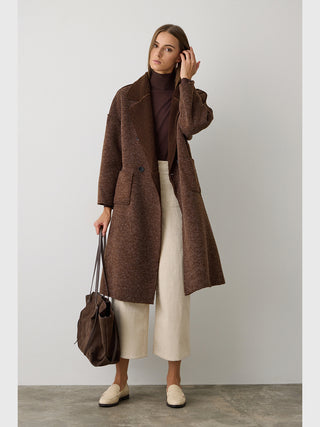 Frau trägt BSB Mantel 215004 chocolate mit zweireihiger Knopfleiste und Reverskragen, kombiniert mit off-white Hosen, beigen Loafers und brauner Tasche, verkörpert einen eleganten, winterlichen Look.
