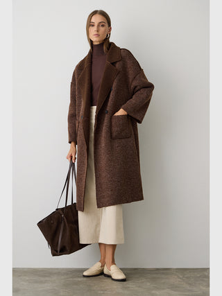 Frau trägt BSB Mantel 215004 chocolate, einen langen, oversized braunen Mantel mit Bouclé-Futter, Patch-Taschen und Reverskragen, kombiniert mit einem dunkelbraunen Rollkragenpullover und einer cremefarbenen Culotte.