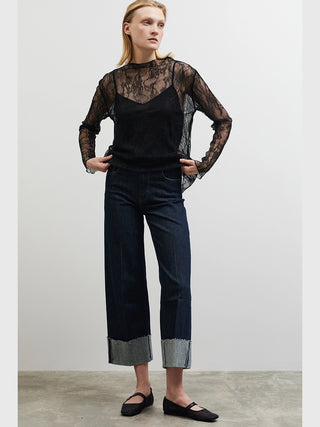 BSB Bluse 210065 black: Modell trägt eine transparente schwarze Spitzenbluse mit langen Ärmeln und floralem Muster über einem schwarzen Top, kombiniert mit hochtaillierten Jeans und schwarzen Flats.