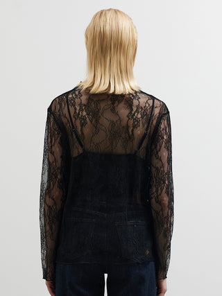 Eine Person trägt die BSB Bluse 210065 black, eine schwarze, transparente Spitzenbluse mit floralen Mustern, kombiniert mit dunkelblauen Jeans, von hinten fotografiert, vor hellem Hintergrund.
