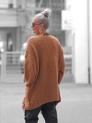 Frau mit silbergrauem Dutt trägt den BSB Cardigan 215013 chocolate, einen lockeren, braunen Teddy-Fleece-Cardigan mit Fransen, ideal für kühle Tage. Kombiniert mit dunkler Hose und silbernen Accessoires.