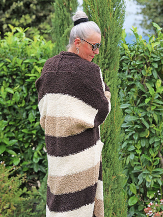Ältere Frau im Freien, trägt den OFF#DLY Cardigan Sandy brown Stripes. Der kuschelige, offene Strickcardigan zeigt breite Streifen in Naturtönen, perfekt für kühle Tage.