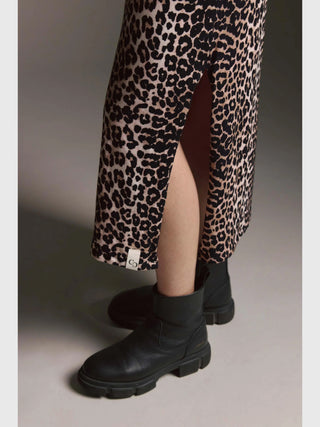 Nahaufnahme von Beinen in einem Cotton Candy Dress Magnolia multicolor, einem Leopardenmuster-Midirock mit seitlichem Schlitz, kombiniert mit klobigen schwarzen Lederstiefeletten.