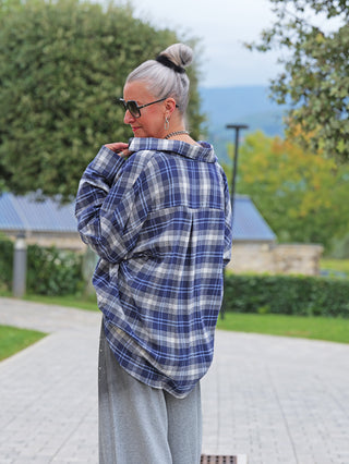 Person im Profil trägt eine OFF#DLY Bluse Greta blau kariert, lässig über weiten, hellgrauen Hosen. Die Bluse hat ein oversized Karo-Muster in Blau-Weiß.