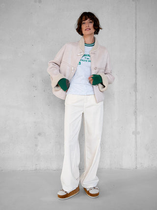 Penn&Ink Jacke W25c321 ecru: Frau trägt eine kuschelige, cremefarbene Jacke mit hohem Kragen. Die lässige Passform kombiniert maximalen Komfort mit sportivem Look. Hände in den Taschen, entspannter Auftritt.