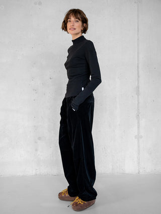 Penn&Ink Longsleeve schwarz, schmal geschnitten mit Stehkragen, aus weichem, elastischem Material, getragen in einer minimalistischen Outfit-Kombination mit locker sitzender Hose und auffälligen Schuhen.