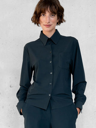 Eine Person trägt die Penn&Ink Bluse antra, eine klassische, knitterarme Bluse mit Hemdkragen und durchgehender Knopfleiste, perfekt für Business und Reisen, kombiniert mit passenden dunklen Hosen.