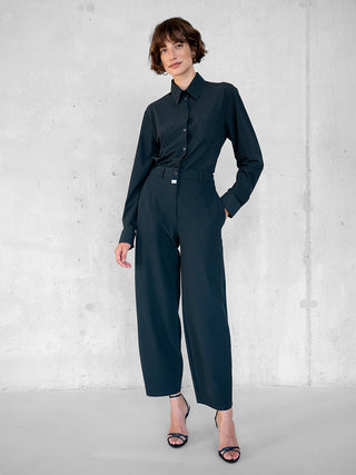 Person trägt Penn&Ink Bluse antra, eine schwarze, langärmelige Bluse mit klassischem Hemdkragen und durchgehender Knopfleiste, kombiniert mit hochtaillierten, weiten Hosen. Minimalistischer, eleganter Look.