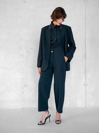 Modell trägt den Penn&Ink Blazer antra, locker drapiert über passendes Hemd und Hose. Der Blazer zeichnet sich durch seine strukturierte Silhouette mit markanten Schultern und Vier-Knopf-Verschluss aus.