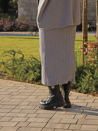 Person trägt den OFF#DLY Rock Linda grey, einen heather-grauen, gerippten Midirock, kombiniert mit schwarzen Kampfstiefeln. Der Rock bietet eine elegante Silhouette und lässigen Komfort.