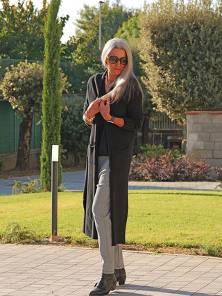 OFF#DLY Strickmantel Laura black: Eleganter, langer schwarzer Strickmantel mit offenem Schnitt und Taschen, getragen von stilvoller Frau mit silbergrauem Haar und rotem Lippenstift, passend für Übergangszeiten.