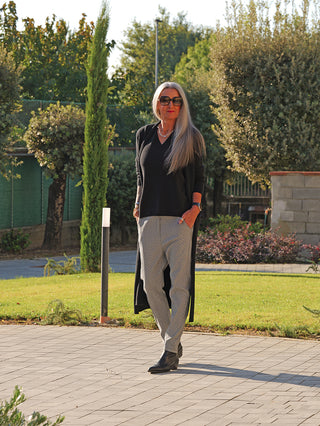 Frau trägt den OFF#DLY Strickmantel Laura black: langer, offener Schnitt mit Taschen, elegante Note zu ihrem Outfit. Ideal für Übergangszeiten, aus weichem Viskose-Mix.