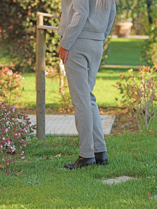 Die OFF#DLY Pant Lina black/white zeigt ein elegantes, grafisches Muster auf einem schmal geschnittenen Bein, getragen mit schwarzen Lederstiefeln, passend für Alltag und Business.