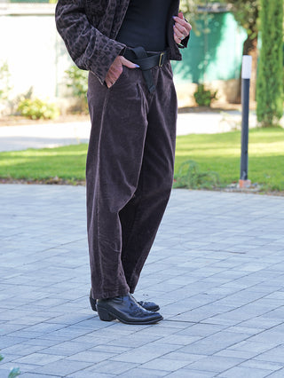 OFF#DLY Pant Vada schoko: Dunkelbraune, weit geschnittene Cordhose mit Retro-Charme, elastischem Bund und Umschlag-Option. Getragen mit einem schwarzen Gürtel und schwarzen, dezent gestickten Stiefeletten.