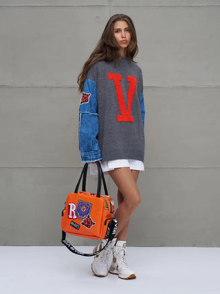 Junge Frau trägt #VDR Knit Sweat 18073 grey mel, ein übergroßer Strickpullover mit orangefarbenem V, Denim-Ärmeln mit Rosenpatches und kombiniert mit kurzem Rock und weißen Sneakers.