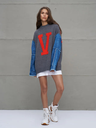 #VDR Knit Sweat 18073 grey mel mit rotem „V“ und blauen Denim-Ärmeln, getragen von einem Model mit weißem Rock und chunky Sneakers vor grauer Wand.