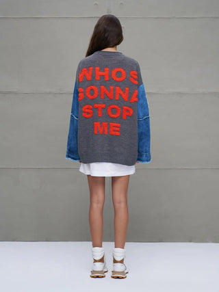 #VDR Knit Sweat 18073 grey mel: Oversize-Strickpullover mit auffälligem roten Schriftzug WHO’S GONNA STOP ME auf dem Rücken und kontrastierenden Denim-Ärmeln, kombiniert mit weißem Rocksaum und klobigen weißen Stiefeln.