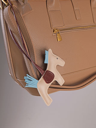 Enrico Coveri Tote Bag in Taupe aus Polyurethan, mit einem hängenden, beige Pferdeanhänger an einem Riemen. Die Tasche hat Henkel und einen Cross-Riemen, ideal für stilvolle Vielseitigkeit.