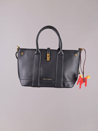 Enrico Coveri Tote Bag black: Strukturierte schwarze Lederhandtasche mit goldfarbener Hardware, zentralem Verschluss und rotem Pferdeanhänger. Zwei Henkel, „ENRICO COVERI“ in Gold unten zentriert geprägt.