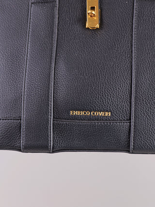 Nahaufnahme der Enrico Coveri Tote Bag black aus schwarzem, genarbtem Leder mit goldfarbener Hardware und geprägtem Logo. Die Oberfläche ist durchgenäht, mit goldener Schließe über dem Logo.
